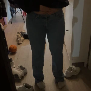 Blå raka jeans med klassisk passform - Säljer ett par blå jeans med rak passform och klassisk femficksdesign. Jeansen har låg midja och är tillverkade i ett tåligt denimtyg. Perfekta för dig som gillar en tidlös och enkel stil.