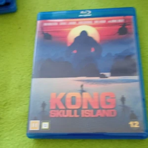 Kong: Skull Island - En actionfylld berättelse om äventyr på en mystisk ö där en gigantisk varelse härskar. Perfekt för dig som gillar spänning, monster och episka äventyr. Omslaget visar en siluett av Kong mot en dramatisk solnedgång och helikoptrar i luften.