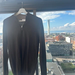 Brun halvziptröja från John Henric - Snygg brun tröja från John Henric med halv dragkedja och ribbad krage. Perfekt för lager-på-lager och passar till både jeans och chinos. Mjuk och skön känsla tack vare ullblandningen. Långärmad modell med klassisk passform.