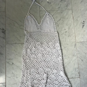 Vit virkad kortklänning med halterneck - Superfin vit virkad kortklänning med halterneck och djup v-ringning.  Strandklänningen är öppen i ryggen 🥰