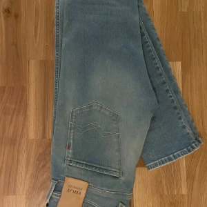 Replay Anbass ljusblå slim jeans - Säljer ett par Replay Anbass Hyperflex jeans i ljusblå tvätt. Passar 29-31. Modellen är slim fit med klassisk femficksdesign och snygga detaljer på bakfickan. Jeansen är tillverkade i stretchigt jeansmaterial som ger en skön passform och rörelsefrihet.