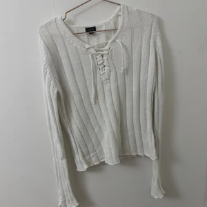 Vit ribbad stickad tröja Lindex S - Vit stickad tröja från Lindex i storlek S. Tröjan har ribbat mönster, snörning vid halsringningen och långa ärmar. 