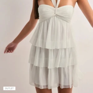 Vit omlottklänning med volanger - Supersöt vit kortklänning från Nelly med flera lager volanger och omlott-detalj upptill. Axelbandslös design med lätt och luftig känsla, perfekt som studentklänning. Bandet går att använd på olika sätt, nästan slutsåld på hemsidan. Aldrig använd och lappen finns kvar, nyskick.🩷