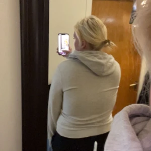 Ljusgrå hoodie med dragkedja - Säljer en ljusgrå hoodie med dragkedja framtill och snörning i huvan. Tröjan har två fickor på magen och är långärmad med ribbade muddar. Perfekt för chill dagar och enkel att matcha med det mesta.