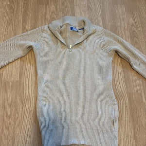 Beige ribbad half zip från Jack & Jones - Snygg beige ribbad tröja från Jack & Jones med half zip i halsen. Tröjan har långärmade ärmar och en hög krage som går att öppna med dragkedja. Perfekt för dig som gillar stilrena och bekväma plagg med lite edge.