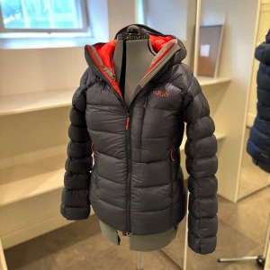 Mörkblå Rab kvinno dunjacka  - Snygg mörkblå dunjacka från Rab i storlek XS med röd insida och huva. Jackan är knappt använd och är i helt perfekt skick. Namn taggen är dock ifylld. Nypris 3300