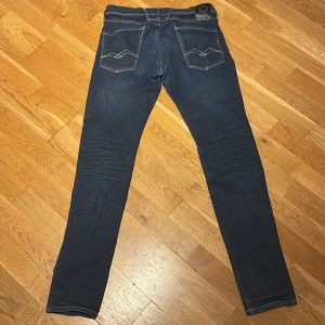 Mörkblå Replay anbass jeans, midja 31/32 - Snygga mörkblå Anbass jeans från Replay. Modellen har raka ben och normal passform, med diskret broderi på bakfickorna. Tillverkade i mjukt jeansmaterial som sitter skönt hela dagen.