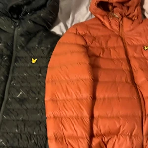Tvp jackor från Lyle & Scott ( orange L) (mörkgrön M) - Jackorna är från Lyle & Scott och orange är storlek L och gröna är storlek M. Jackorna har quiltad design, huva och dragkedja framtill. Ikonisk gul logga på bröstet. Perfekt för kyliga dagar och ger en snygg streetstyle-vibe.