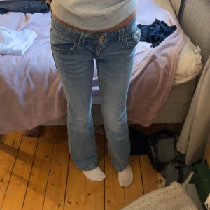 Ljusblå bootcut jeans Gina Tricot - Snygga ljusblå jeans från Gina Tricot med bootcut passform och låg midja. Klassisk femficksmodell med silverfärgade knappar och bälteshällor. Jeansen är tillverkade i mjukt denimtyg som sitter skönt och har en cool, avslappnad vibe.