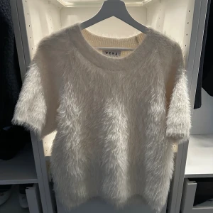 Fluffig T-shirt  - Supermjuk och fluffig vit tröja från Wera med korta ärmar och rund hals. Tröjan har en cool pälsliknande yta som ger en unik look och passar perfekt när du vill sticka ut lite extra. Perfekt för dig som gillar trendiga och mysiga plagg.