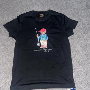 Svart Polo Bear t-shirt från Ralph Lauren - Helt ny T-shirt från Ralph lauren, bara testad annars aldrig använt. Den satt lite för liten på mig, jag är 191cm lång väger ca 78kg. Skriv vid intresse! (Går ner i pris vid snabbt köp!)