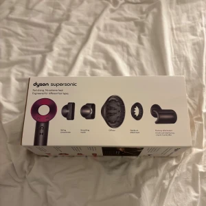 Dyson Supersonic - Dyson Supersonic hårfön i mycket fint skick, komplett med originaltillbehör: styling concentrator, smoothing nozzle, diffuser, gentle air och flyaway attachment. Snabb torkning utan extrem värme, passar alla hårtyper. Inga synliga defekter eller slitage, levereras i originalförpackning.