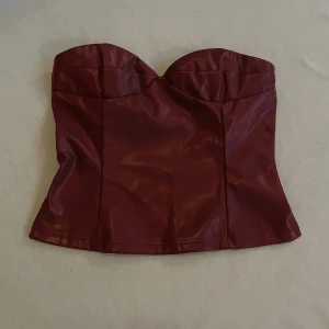 Vinröd skinntopp - Jag säljer min vinröda korsett-topp, den är bara använd ett fåtal gånger och är super snygg! Köp nu jag postar snabbt!!💗💗