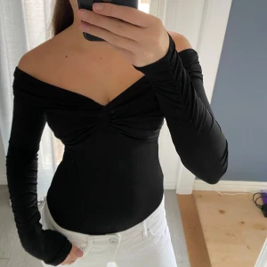 Svart offshoulder topp med twist - Säljer en svart offshoulder body med snygga detaljer. Helt ny och aldrig använd