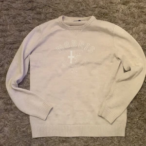 Beige stickad tröja från Morris - Säljer en beige stickad tröja från Morris med broderad logga och emblem framtill. Tröjan har rund halsringning, ribbade muddar och är långärmad. Perfekt för dig som gillar klassisk och stilren design. storlek L men passar bättre i M . Tröjan är i väldigt bra skick. Pris kan diskuteras, hör av dig vid frågor!