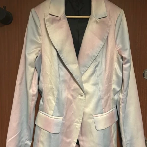 Pastellfärgad kavaj med knappar - Snygg kavaj i skimrande pastellfärger med mjuka övergångar mellan ljusblått, rosa och vitt. Klassisk modell med breda slag, två fickor fram och fyra vita knappar vid ärmslutet. Materialet har en satinliknande finish som ger en lyxig känsla.