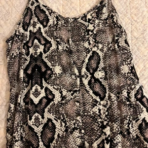 Snakeprint topp från Amisu - Snygg ärmlös topp från Amisu i storlek XS med coolt ormskinnsmönster i svart, grått och beige.  Lätt och skönt material.☺️