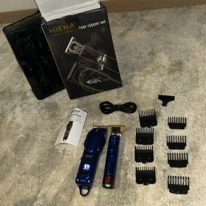 HIENA Hair Clipper Set - Komplett HIENA hårklippare och trimmer-set med digital display, flera kammar, USB-laddkabel och tillbehör. Passar för hår, skägg och kropp. Snygg design, ser ut att vara i mycket gott skick. Perfekt för både hemmabruk och professionell styling. Priset kan diskuteras:)
