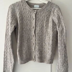 Flätad kofta - Jättefin beige/brun kofta i flätat mönster, perfekt året om! Sitter en mörkare insydd tråd/garn på högra axeln, fanns där när jag köpte koftan förra året, går nog att ta upp eller lappa över med garn💕