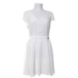 Vit spetsklänning från Chiara Forthi - Supersöt vit kortklänning från Chiara Forthi med spets upptill och v-ringad hals. Kjolen är lätt och flödande, och ryggen har en snygg öppen detalj med knappar. Perfekt för sommarens alla tillfällen när du vill känna dig extra fin. 