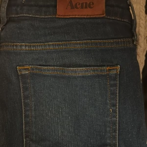 Mörkblå jeans från Acne Studios - Snygga mörkblå jeans från Acne Studios med klassisk femficksdesign och silverfärgade nitar. Jeansen har en rak passform och är tillverkade i slitstarkt denim med subtila tvättade detaljer. Perfekt för dig som gillar stilrena och tidlösa jeans. Storlek 30/32