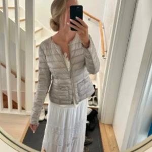 Vintage jacka  - Snygg beige jacka med quiltade detaljer och dragkedja framtill. Jackan har rund hals, två fickor med dragkedja och långärmad design. Perfekt för dig som vill ha en lätt och stilren jacka till kyliga dagar. Första bilden är lånad men sitter så på