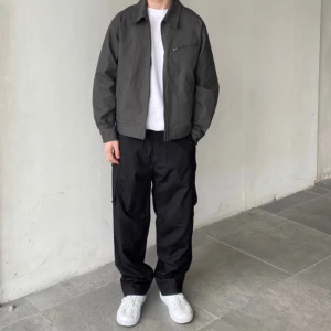 Helt ny Mörkgrå zip-up jacka från Uniqlo - Säljer en stilren mörkgrå jacka från Uniqlo i bomullsmix med dragkedja framtill och bröstficka med zip. Jackan har klassisk krage och en clean look som passar till många outfits. Perfekt för lager-på-lager och enkel att matcha. 