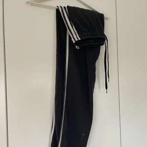 Svarta Adidas mjukisbyxor med vita ränder - Svarta Adidas mjukisbyxor, strl S. Använda men i bra skick, bra pris!