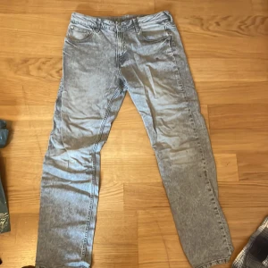 Grå tapered jeans från H&M, strl 170 - Snygga grå jeans från H&M med relaxed fit och tapered leg. Modellen har justerbar midja och klassisk femficksdesign. Jeansen har en tvättad look och passar dig som gillar en chill och modern stil.