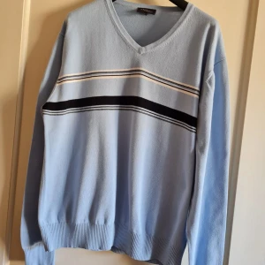 Ljusblå tröja från Atlant strl L - Säljer en ljusblå tröja från Atlant med v-ringning och ett stilrent randigt mönster i svart och vitt över bröstet. Tröjan har långa ärmar och ribbade muddar vid ärmslut och nederkant. 100% bomull. Storlek L (känns liten i storlek). Kan hämtas i Vallentuna.