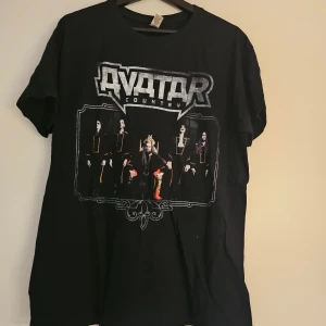 Avatar Country World Tour t-shirt 2018 - Svart t-shirt med tryck från Avatar Country World Tour 2018. Framsidan har stort Avatar Country-logga och bild på bandet, baksidan visar turnédatum och städer. Köpt på Avataras officiella hemsida.