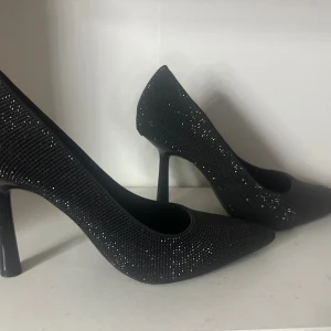 Svarta glittriga klackar från Zara - Snygga svarta klackar från Zara med spetsig tå och hög klack. Skorna är täckta av små glittriga stenar som ger en riktigt festlig känsla. Perfekta för dig som vill sticka ut med stil. Använd en halv utekväll, då det var lite för stora och ovant för mig ‼️