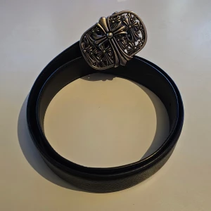 Chrome Hearts Bälte - Bältet är i syntetiskt läder. Buckle är i stål. 105cm lång