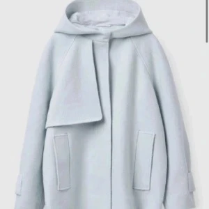 Cos kappa -Ljusblå ullkappa med huva  - Super fin kort kapp från COS! Väldigt fint skick med inga slitningar. Snygg ljusblå kappa med huva och stora fickor framtill. Tillverkad i mjuk ullmix som håller dig varm! Nypris är 2000-3000kr 