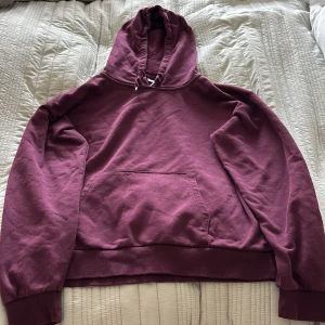 Vinröd hoodie från Gina Tricot - Mysig vinröd hoodie från Gina Tricot med huva och snörning. Tröjan har en stor magficka och ribbade muddar vid ärmslut och nederkant. Perfekt för chill dagar och enkel att matcha med jeans eller mjukisbyxor.