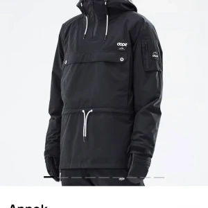 Svart jacka från Dope - Svart jacka från Dope med huva, vita snören och dragkedja vid halsen. Jackan har en stor ficka framtill med knappstängning och en mindre ficka på ärmen med dragkedja. Perfekt för skidåkning eller häng i backen. 