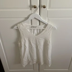 Vit ärmlös topp Selected Femme - Säljer en stilren vit ärmlös topp från Selected Femme i storlek 38. Toppen har v-ringning och är tillverkad i ett mjukt, lätt material som känns skönt mot huden. Perfekt för en fräsch och enkel look och är så snygg som en fest topp till en snygg kjol. 