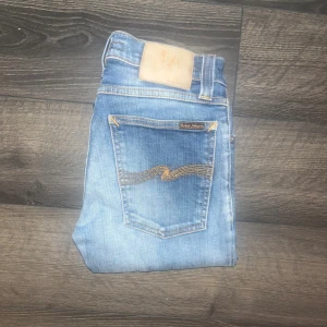 Nudie jeans  - Snygga blå jeans från Nudie Jeans, modell Tight Long John Super Blue. De har en skinny passform med klassiska fem fickor, gul kontrastsöm och Nudie-logga på bakfickan. Materialet är 98% bomull och 2% elastan för extra stretch och komfort. Ifall det inte finns någon bild i annonsen där jag bär plaggen jag säljer så är det för att jag ej kan ha storleken heller passformen, så kolla måtten för storlek och googla på modellnamnet för passform 😉Midja 32cm, längd 100cm. S3