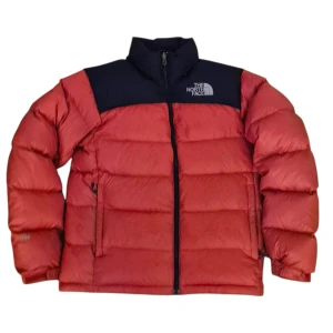 Röd dunjacka från The North Face - Säljer en riktigt fet röd dunjacka från The North Face med svart axelparti och hög krage. Jackan har dragkedja framtill, två sidofickor och är fylld med dun för maxad värme. Perfekt för kalla dagar och snygg streetstil.