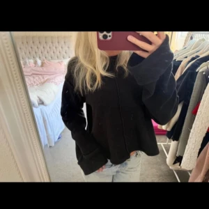 Svart stickad tröja  - En svart stickad tröja med breda ärmslut och synlig söm framtill. Tröjan har en loose passform och rund halsringning, perfekt att slänga på sig till jeans. Enkel och stilren design som funkar året runt.