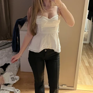 Vit korsett-topp med snörning - Supersöt vit korsett-topp med tunna axelband och snygg snörning i ryggen. Toppen har en markerad byst, lätt utsvängd nederdel och romantisk v-ringning. Perfekt för dig som gillar en feminin och trendig look.