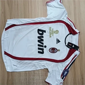 AC Milan Kaka' 22 vit bortatröja Adidas S - AC Milan bortatröja med Kaka' 22-tryck, tillverkad av Adidas. Tröjan är vit med röda och svarta detaljer, klubbmärke och Champions League-brodyr på bröstet. Kortärmad modell i lätt och ventilerande material, perfekt för fotbollsfans.