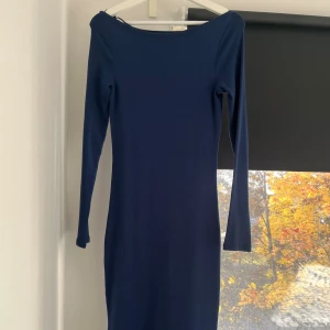 Marinblå långärmad klänning Gina Tricot - Snygg marinblå långärmad klänning från Gina Tricot i storlek S. Klänningen har en smickrande, figurnära passform och är tillverkad i mjuk, ribbad bomull. Enkel och stilren design med rundad halsringning och slät yta.