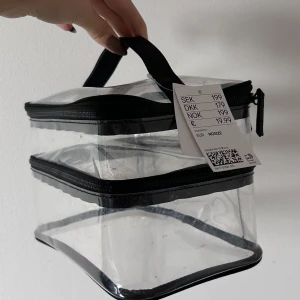 Transparent neccesär  - Snygg transparent neccesär med svarta detaljer och två separata fack med dragkedja. Endast lagt in smink för att se om de skulle få plats (lite fläckig som syns på bild)