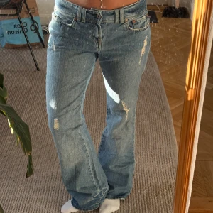 Blå bootcut jeans Polo Ralph Lauren - Säljer ett par blå bootcut jeans från Polo Jeans Company by Ralph Lauren. Jeansen har slitna detaljer, klassisk femficksmodell och låg midja. Tillverkade i bomull med snyggt tvättad finish och råa kanter nertill. Perfekta för en avslappnad och trendig look.