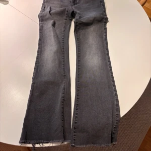 Grå bootcut jeans från Hunkydory - Snygga grå jeans från Hunkydory med bootcut passform och råa, fransiga benslut. Jeansen har en tvättad look och klassisk femficksdesign. Perfekta för dig som gillar en avslappnad men trendig stil.