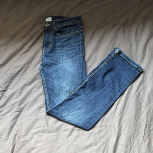 Blå jeans från Pier One, storlek 28/30 - Snygga blå jeans från Pier One i klassisk femficksmodell. Jeansen har kontrastsömmar, raka ben och slim fit passform. Tillverkade i bomull med en skön känsla och stilren look. Perfekta för dig som gillar enkel och tidlös denim.