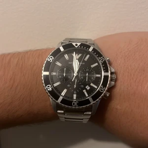 Emporio Armani svart/silver herrklocka - Snygg kronografklocka från Emporio Armani med svart urtavla och silverfärgade detaljer. Robust boett och länkarmband i rostfritt stål. Klockan har flera subdials, datumvisning och tydliga indexmarkeringar. Perfekt accessoar för dig som gillar stilren design. Ordinaire priset är 3800kr.