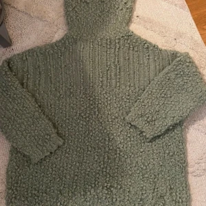 Grön stickad polotröja - Mysig grön stickad polotröja och långärmad. Tröjan har en chunky, bubblig struktur. Knappt använd