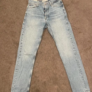 Ljusblå jeans från Jack & Jones - Säljer ett par ljusblå jeans från Jack & Jones med klassisk femficksdesign och knappgylf. Jeansen har raka ben och är tillverkade i bomull. Nyskick 